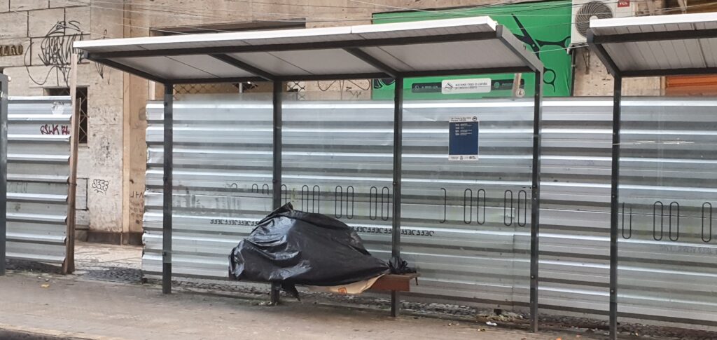 Senhora dorme coberta em parada de ônibus. Foto: Wagner Oliveira